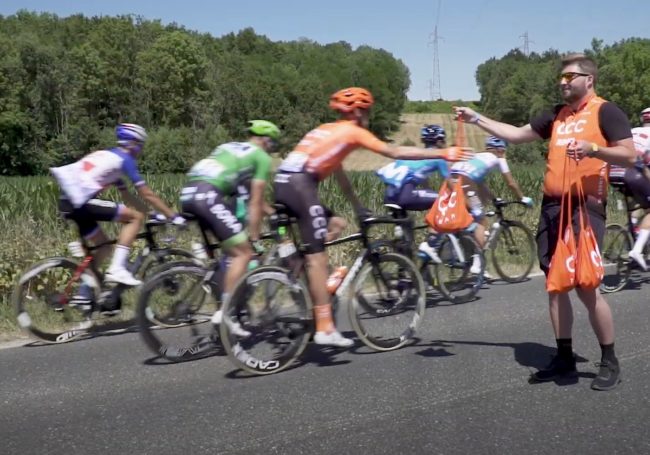 pro cyclist grabbing musette bag in the feed zone