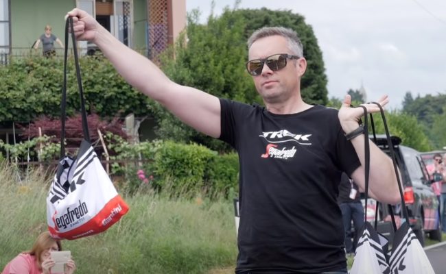 soigneur holding a musette bag and waiting for a cyclist to grab it