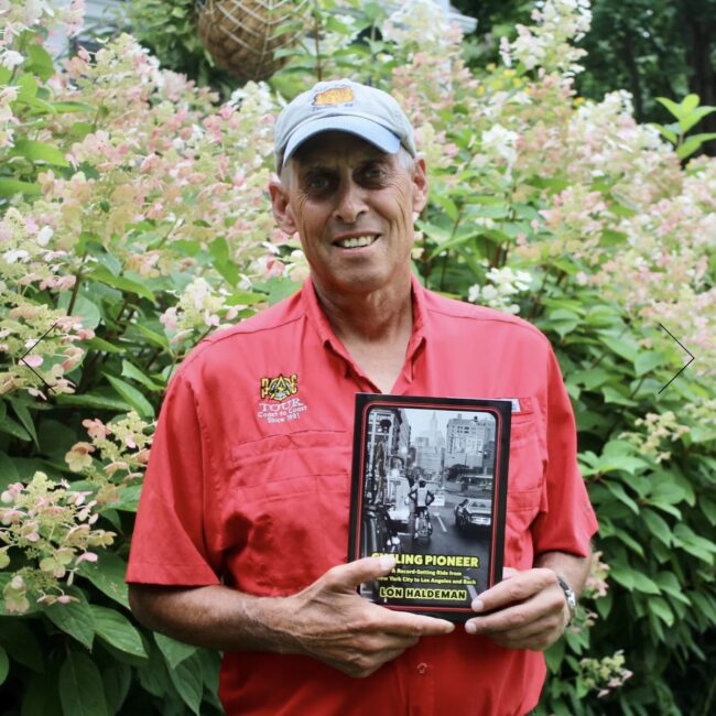 Lon Haldeman holding his book cycling pioneer