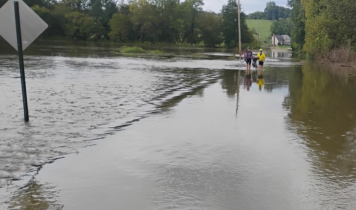 flooded roads cyclists carrying bikes on flooded streets